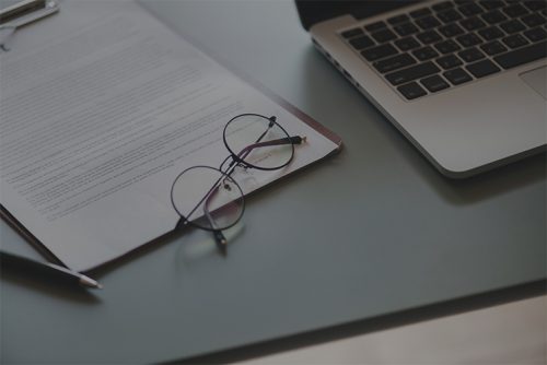 Desk with laptop, glasses and notebook