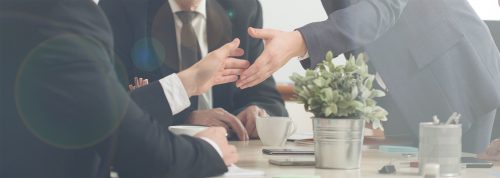 Two people in suits shaking hands during a meeting